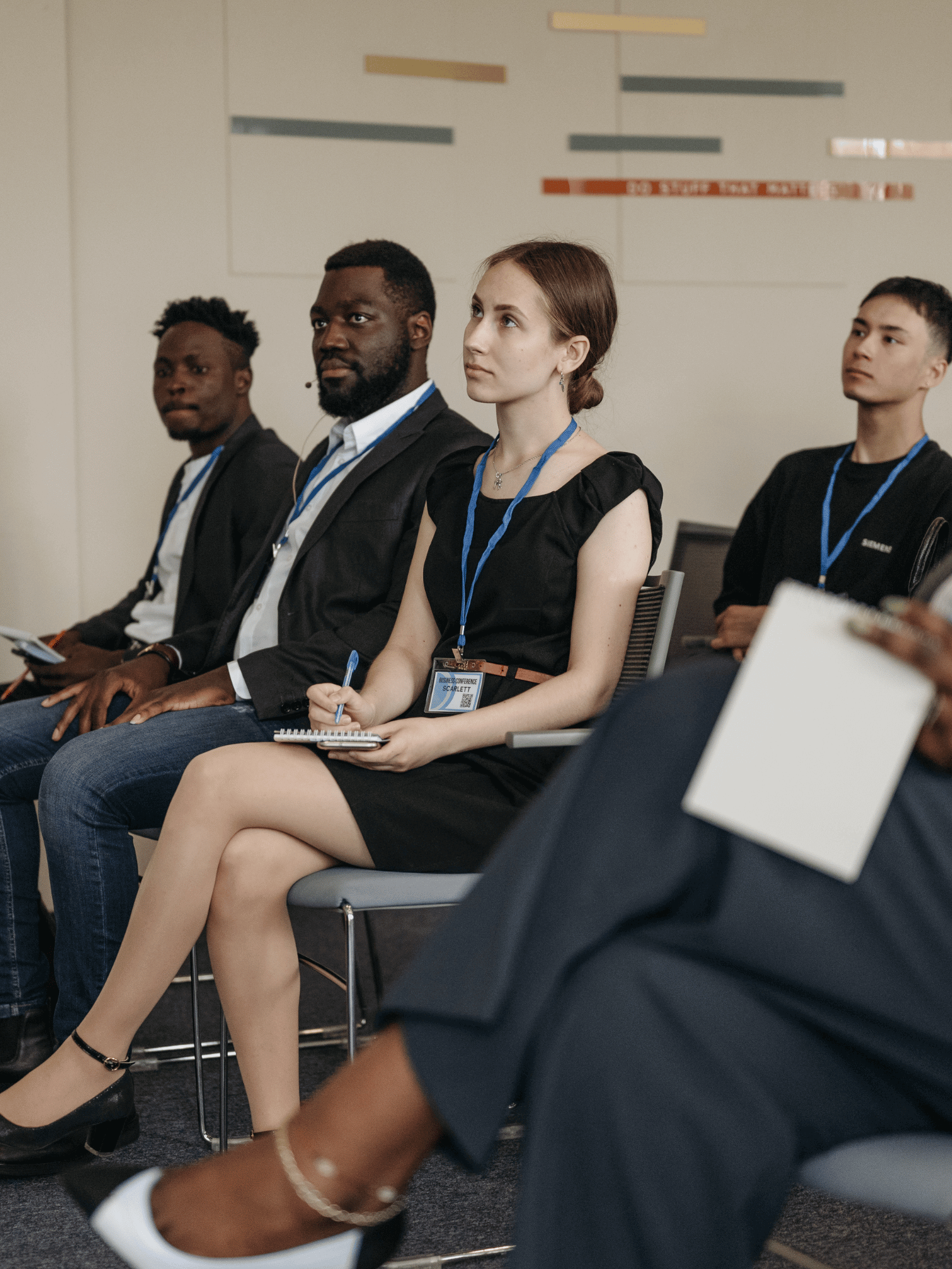 A group people setting in chairs listening to a speaker intently.