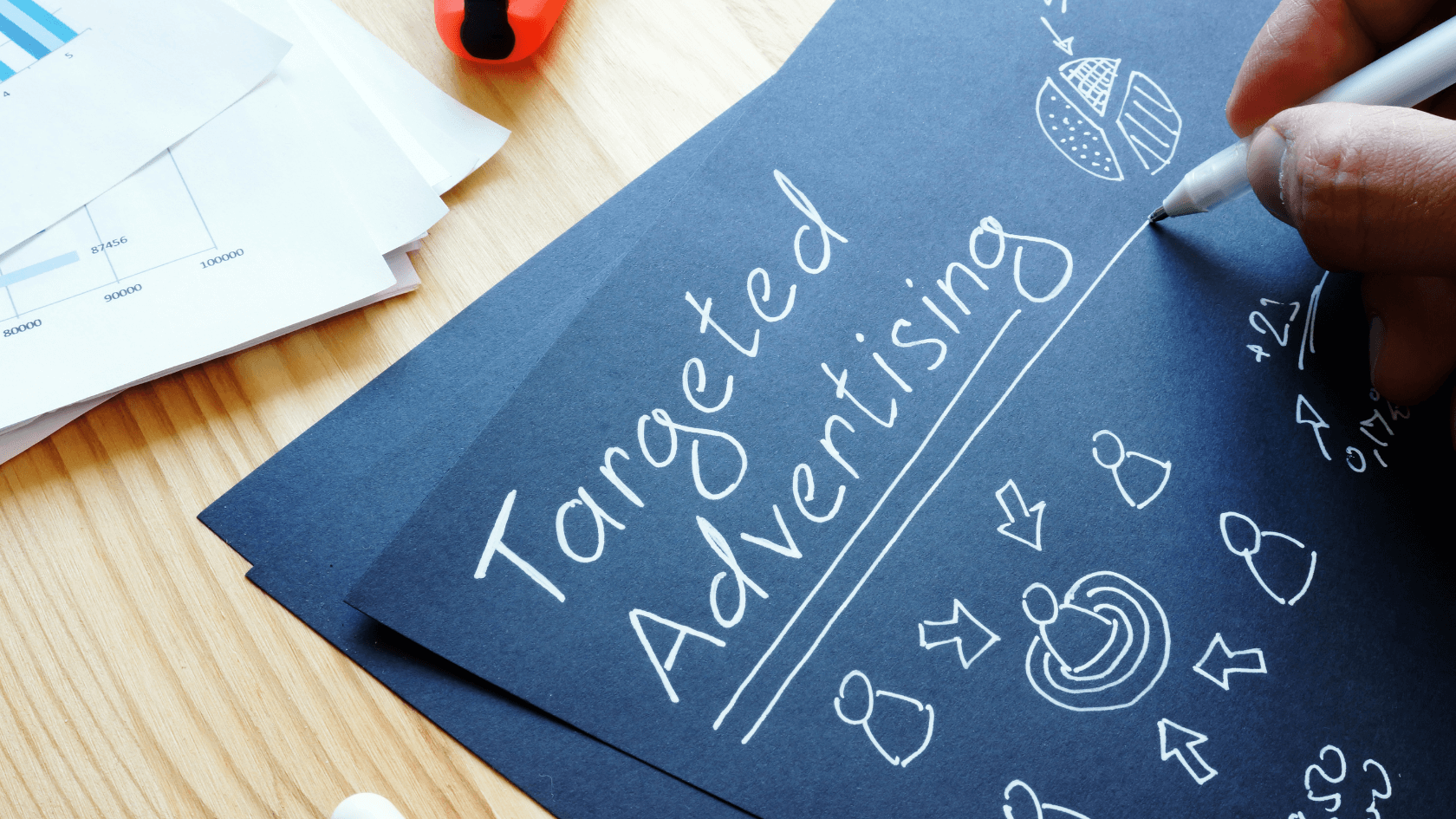 A black sheet of paper with an advertising strategy and someone writing on it.