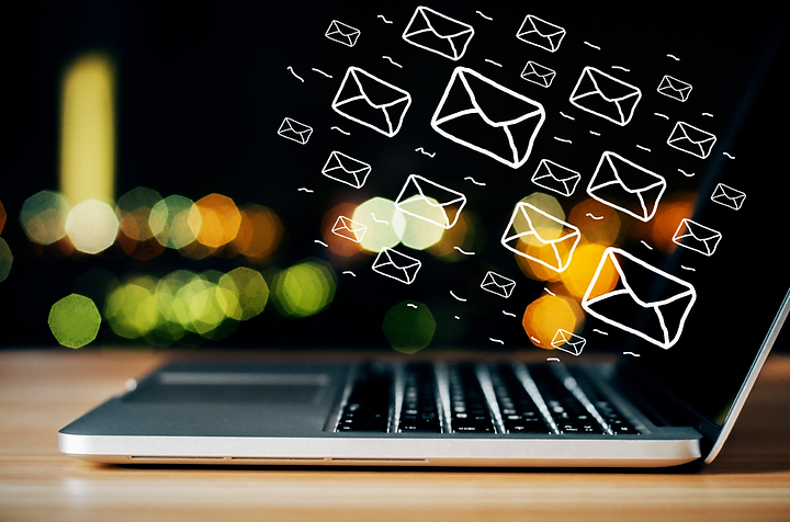 Email icons flying out of an open laptop at night, representing email marketing outreach
