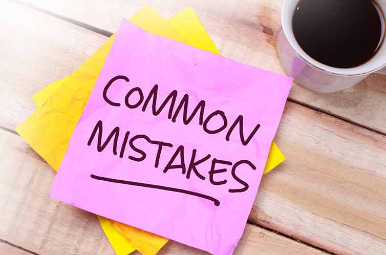 "Common Mistakes" written on a pink sticky note next to a cup of coffee on a desk