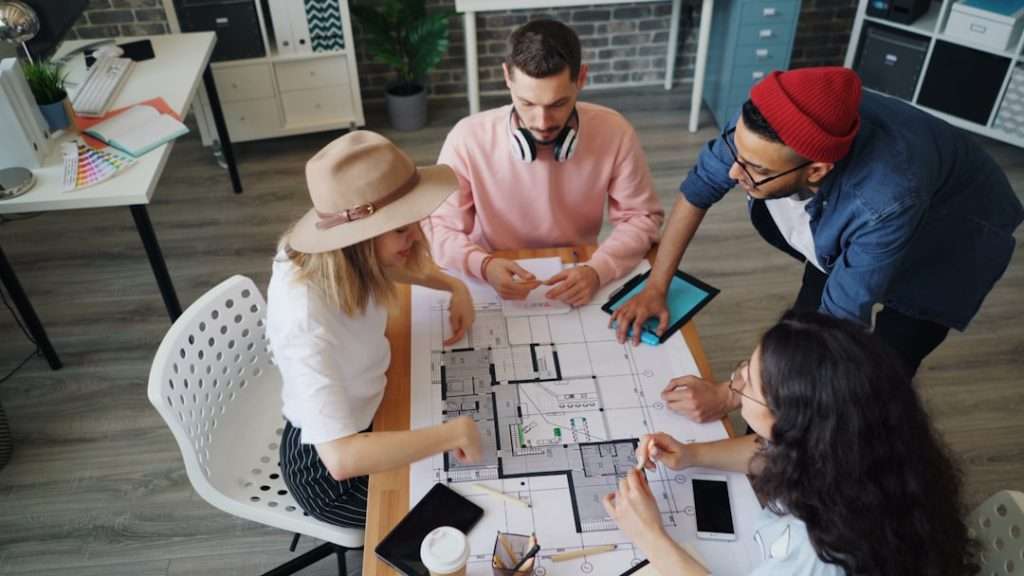 Team collaboratively reviewing floor plans and blueprints in an office setting